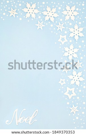 Silver noel sign on pastel blue background border with snowflakes. Festive composition for winter, Christmas & the New Year holiday season. Top view, flat lay, copy space.