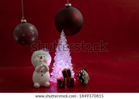 A snowman with presents and a Christmas tree.Christmas scene on a red background.