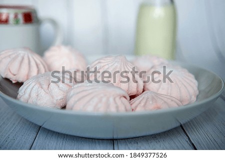 Pink marshmallows on a white plate. White and pink sweet homemade marshmallows or zephyr. Side view. Selective focus.
