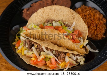 Tacos. Crispy flour and corn tortillas filled with sausage, bacon, beef, cheese, sour cream, salsa and guacamole and served with rice and beans. Classic Tex-Mex or Mexican restaurant entrée favorite. Royalty-Free Stock Photo #1849380016