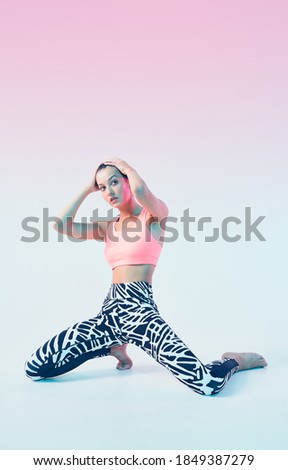 Sporty fit girl in stylish sportswear posing in neon light. Leggings for effective exercising, female wellness
