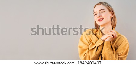 So cute, heart melts from cuteness. Tender good-looking woman in beige shirt, clenching hands together near chest, tilting head and smiling with warm expression, moving while looking at kitten