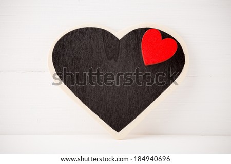 Board in the form of heart on a white wooden background.