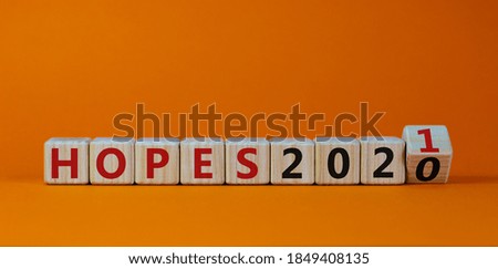 Business concept of planning 2021. Fliped a wooden cube and changed the inscription 'Hopes 2020' to 'Hopes 2021'. Beautiful orange background, copy space.
