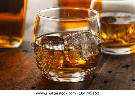 Alcoholic Amber Whiskey Bourbon in a Glass with Ice Royalty-Free Stock Photo #184945160