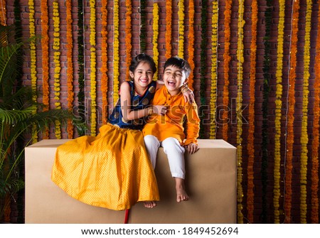Indian kids, little brother and sister celebrating Diwali, Raksha Bandhan, Bhai Dooj with big gift box and sweet laddoo Royalty-Free Stock Photo #1849452694