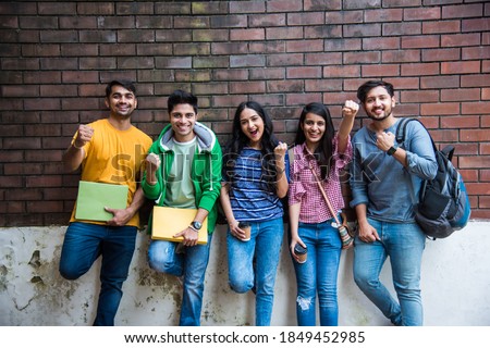Cheerful Indian asian young group of college students or friends laughing together while sitting, standing or walking in campus Royalty-Free Stock Photo #1849452985