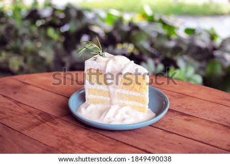 Piece of layer sponge vanilla cream cake topped with fresh coconut meat sliced on plate. Selective focus.