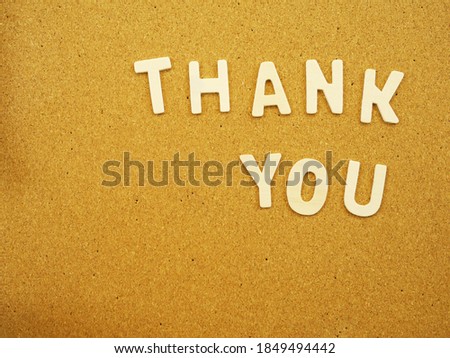 Word "Thank you" by wooden alphabets on cork board with copy space