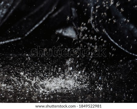 Water splash on black background. Drops of water on a dark glass texture.
