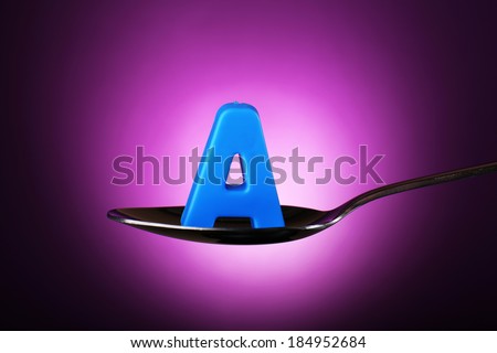 Letter A in silver spoon on purple background