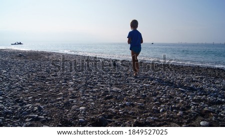 A child photographs a dove on a deserted beach in November.