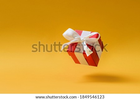 Red jewelry box levitating on a yellow background with copy space.
