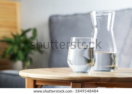 Jug and glass of water on wooden table in room, space for text. Refreshing drink Royalty-Free Stock Photo #1849548484