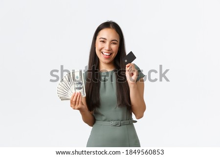 Small business owners, women entrepreneurs concept. Pleased asian woman prefer buying things and shopping with contactless payment, choosing credit card instead of cash, holding money