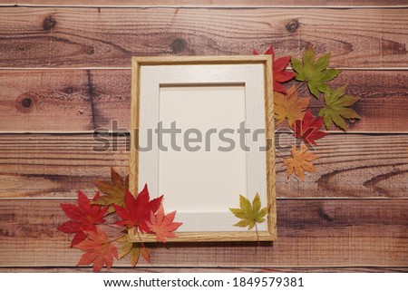 Autumn leaves with blank frame on the wood table. Autumn background.