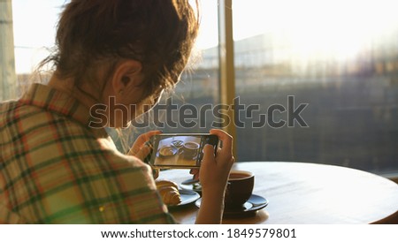 Close up of woman holds modern smartphone and taking pictures of her morning breakfast coffee and tasty croissant buns to share photos on social media resources