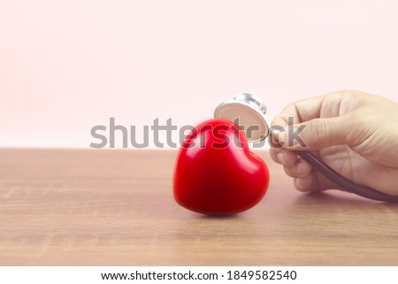 Close up hand to use medical stethoscope checking the red heart .Concept of a physical examination and health safety insurance.