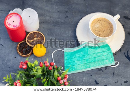 Medical mask, Christmas accessories, a cup of coffee. Layout on a black table. Concept celebrating the New Year during coronavirus, be careful