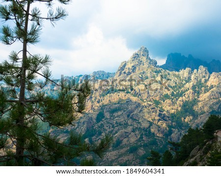 Mountains with rain clouds and fir trees in the Bavella region in Corsica, France.