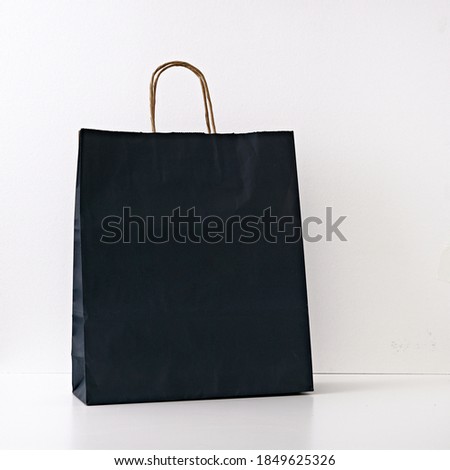 Gift black paper bag on a white background. Copy space, flat lay, mock up, top view