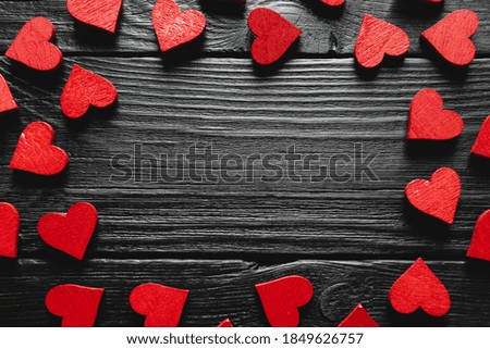 Frame of hearts on black wooden background, copy space