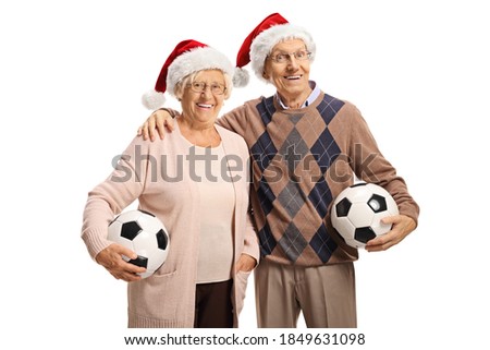 Elderly couple wearing santa claus hats and holding soccer balls isolated on white background