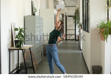 Hooray! Overjoyed excited millennial female office worker manager employee laughing screaming at hall corridor feeling happy of receiving job, signing profitable contract, getting reward for good work