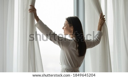 I managed it! Satisfied successful young woman renter buyer owner tenant of modern house flat apartment standing by large window at morning after first night at new home feeling content happy proud