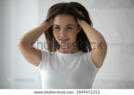 Thick and healthy. Long-haired millennial woman standing by mirror burying hands to her lovely shiny hair, female client is satisfied by result of regular use of professional beauty haircare products Royalty-Free Stock Photo #1849651252