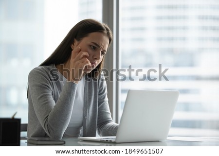 Pensive sad millennial woman office employee responsible manager spending time at office desk frowning looking at pc screen unable to find correct decision answer wrestling with difficult hard problem Royalty-Free Stock Photo #1849651507