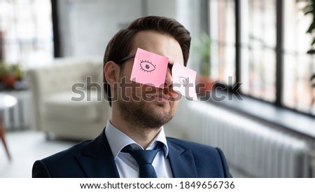 Head shot close up exhausted 30s businessman manager employee sitting in office with paper stickers on eyeglasses, fallen asleep after hard working overload day in office, fatigue burnout concept. Royalty-Free Stock Photo #1849656736