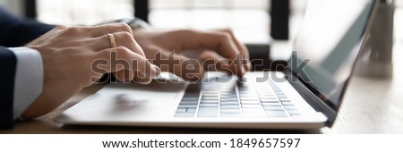 Close up wide banner image young businessman using computer, typing message on keyboard, web surfing information in internet or working on online project, modern technology in office working lifestyle