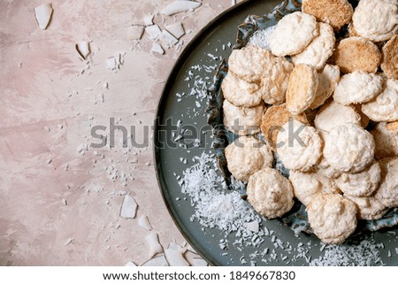 Homemade coconut gluten free cookies with coconut flakes on ceramic plate over pink texture background. Flat lay, copy space