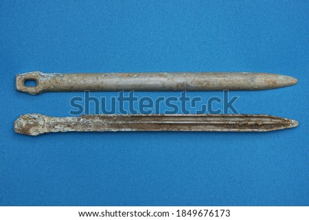 two old gray aluminum army german tent pegs lie on a blue table