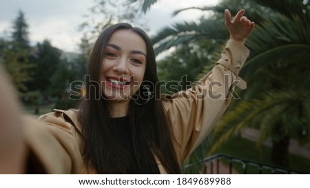 Young smiling face woman holding camera or phone in hand and she pointing out and she makes video call or she is recording video for her fans, she is surprised suddenly, video call and vlogger concept