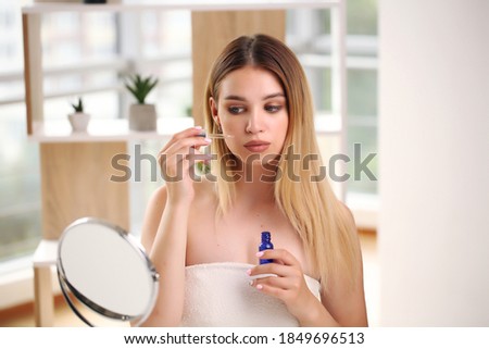 Skincare concept, portrait of happy female applying cosmetic oil on face.