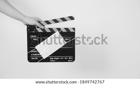 Hand is hold clapper board or movie slate with face mask. it use in video production and cinema industry on white background.In black and white picture.