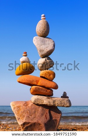 Rock zen Pyramid of balanced stones against the background of the sea and blue sky. Concept of balance, harmony and meditation