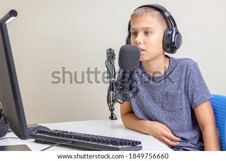 Teenager wearing headphones talk using microphone. Boy recording podcast, online learning from home