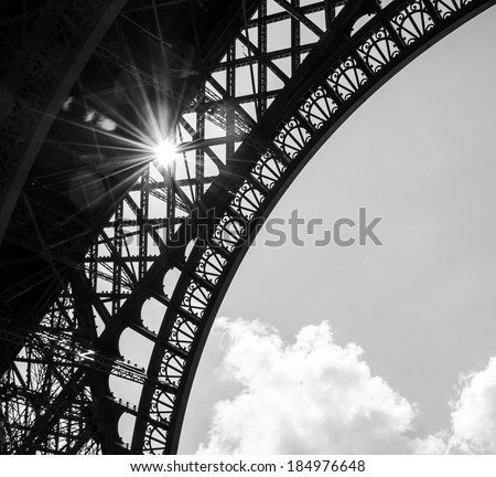 Sun shining through Eiffel Tower. Sun beams and spots. Aged photo. Black and white.