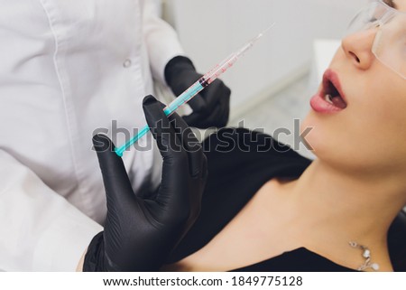 Dentist giving injection for anesthetizing his patient.