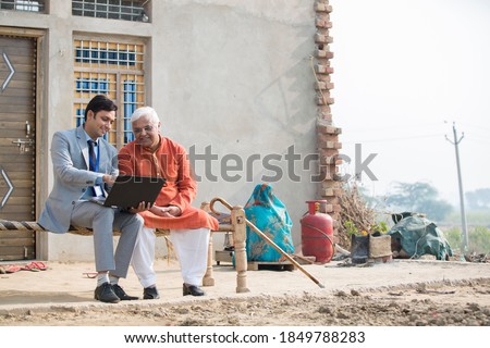 Real agent showing online content on laptop to farmer