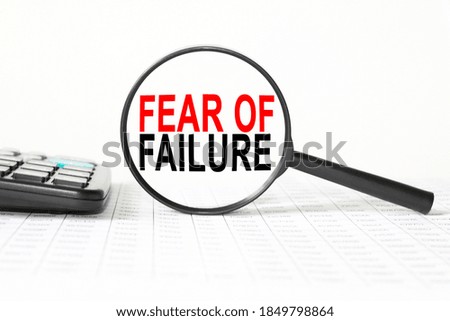 words FEAR OF FAILURE in a magnifying glass on a white background. business concept