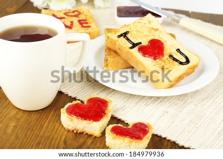 Delicious toast with jam and cup of tea on table close-up