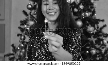 A woman lights sparklers against the background of a Christmas tree decorated for the holiday. Celebrating winter holidays
