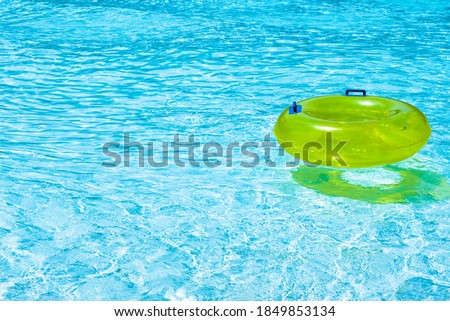 Yellow Inflatable ring floating in the swimming pool on a sunny day, summer vacation concept.