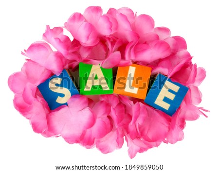 SALE concept spelled out in colorful toy blocks nestled in pink fabric flower petals.