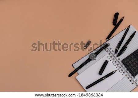 Modern office desk workplace with blank notebooks, pens, wrist watch usb memory card . Copy space on brown wood grain surface background. Top view. Flat lay style. . High quality photo