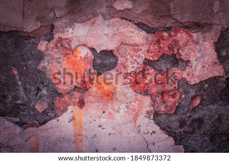 The crumbling texture of a colorful stone wall. Cracks and destruction of gypsum facing material. The background is grayed out and contains noise and graininess.